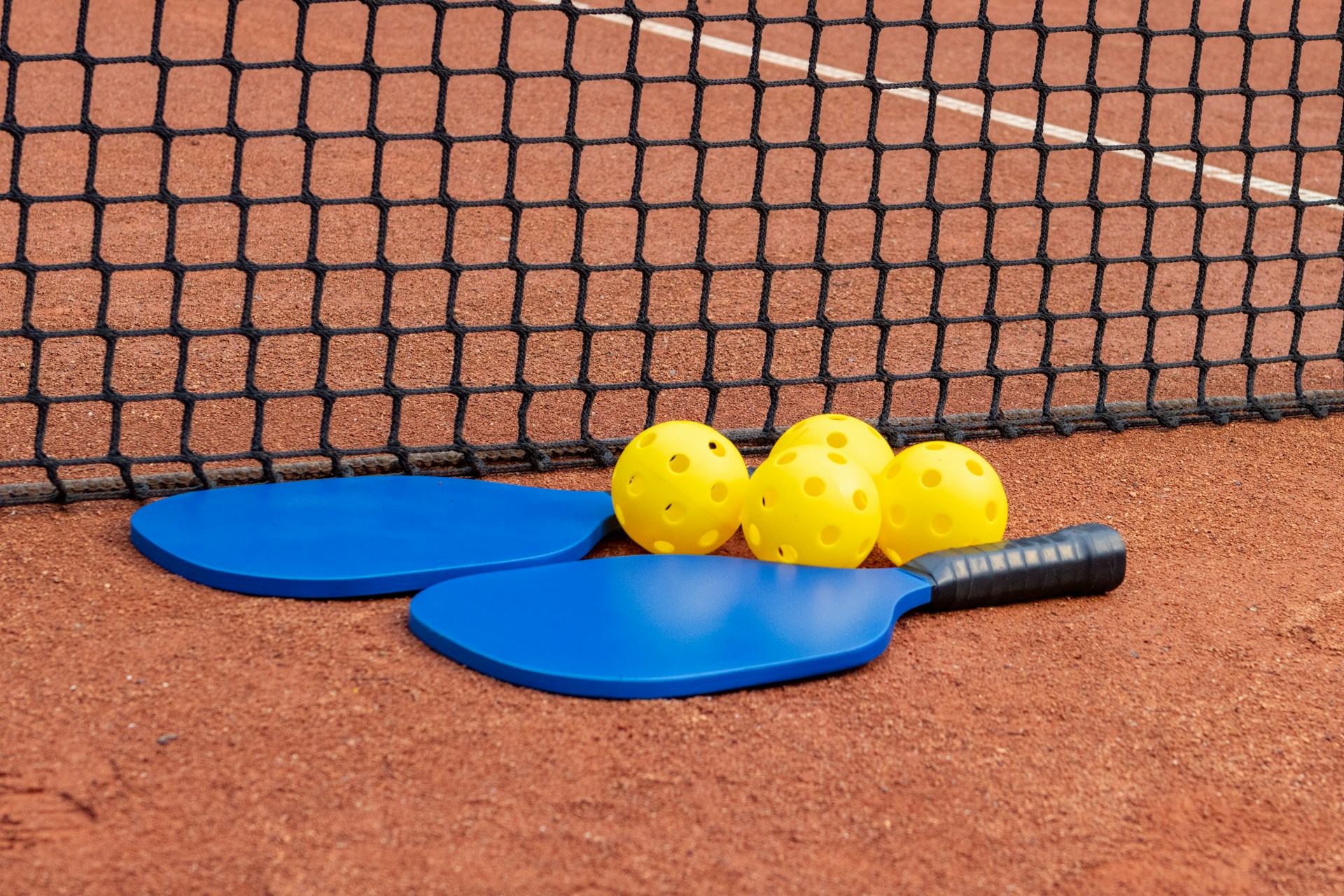 Paddle and balls on court as pickleball terminology is explained